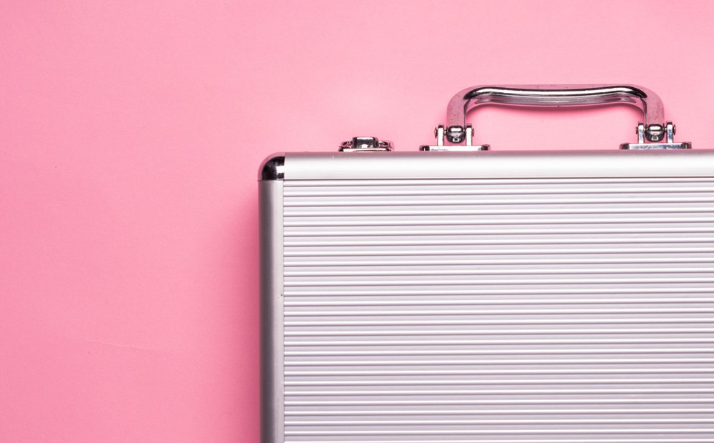 A silver briefcase against a pink background