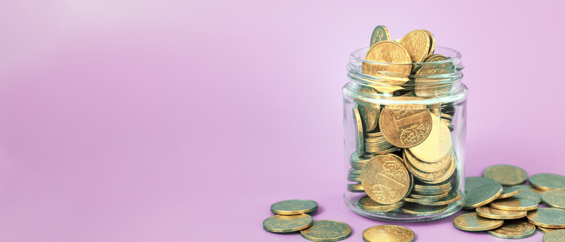 Image of coins in a glass jar on a pink background