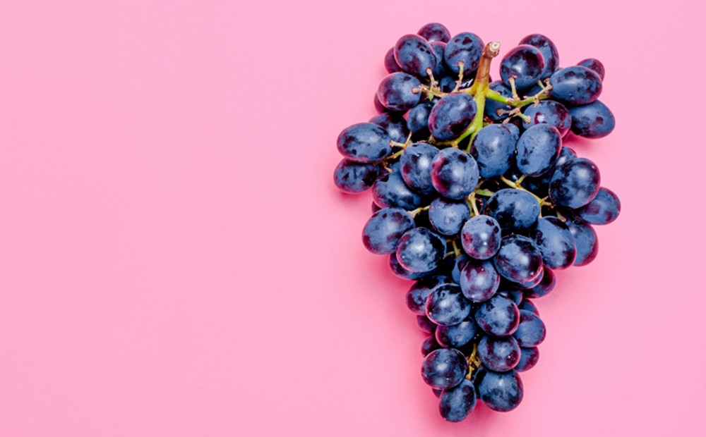 Image of black grapes against a pink background