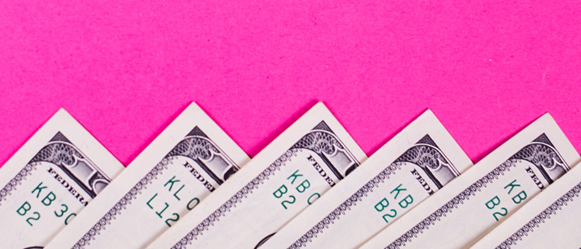 Image of money notes spread out on a pink background