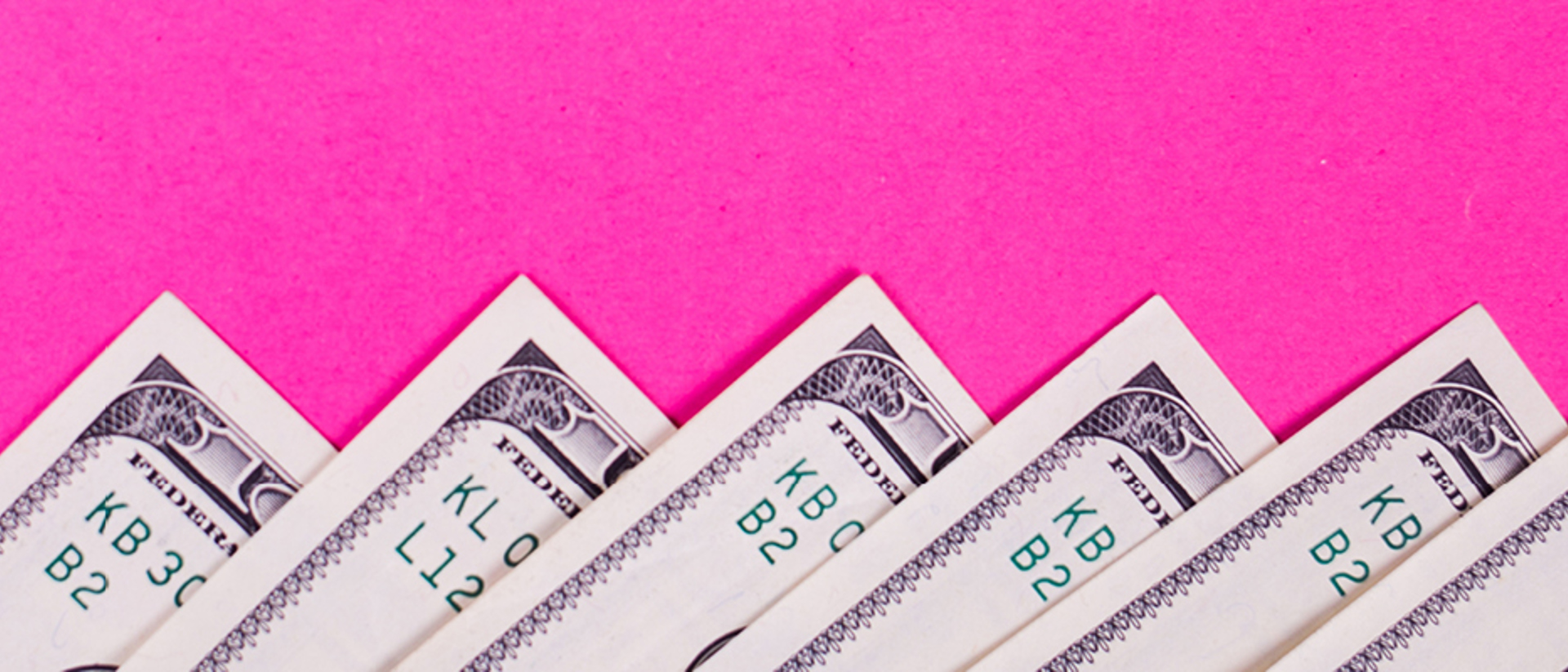 Image of money notes spread out on a pink background