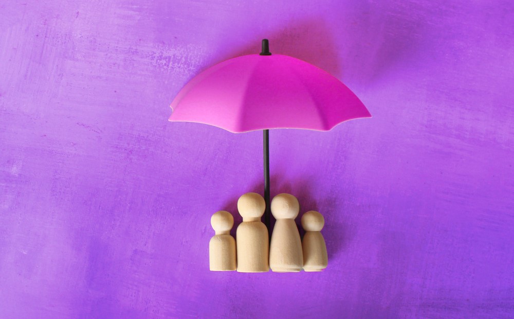 Wooden figures under a purple umbrella against a purple background