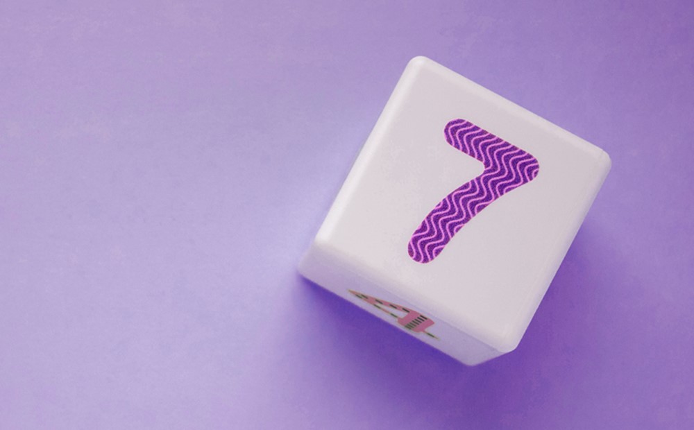 Image of the number 7 on a dice against a purple background