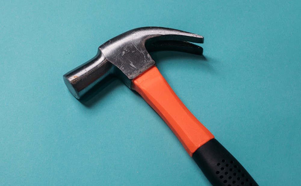 An orange hammer against a teal background