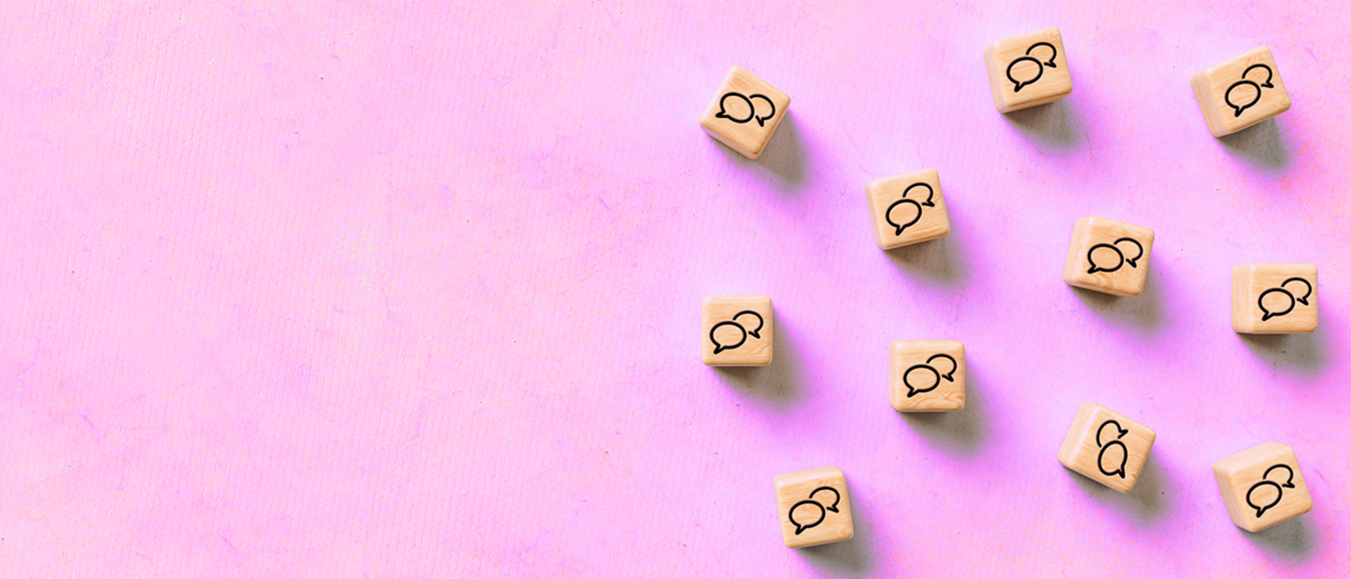 Image of wooden cubes with speech bubbles on a pink background