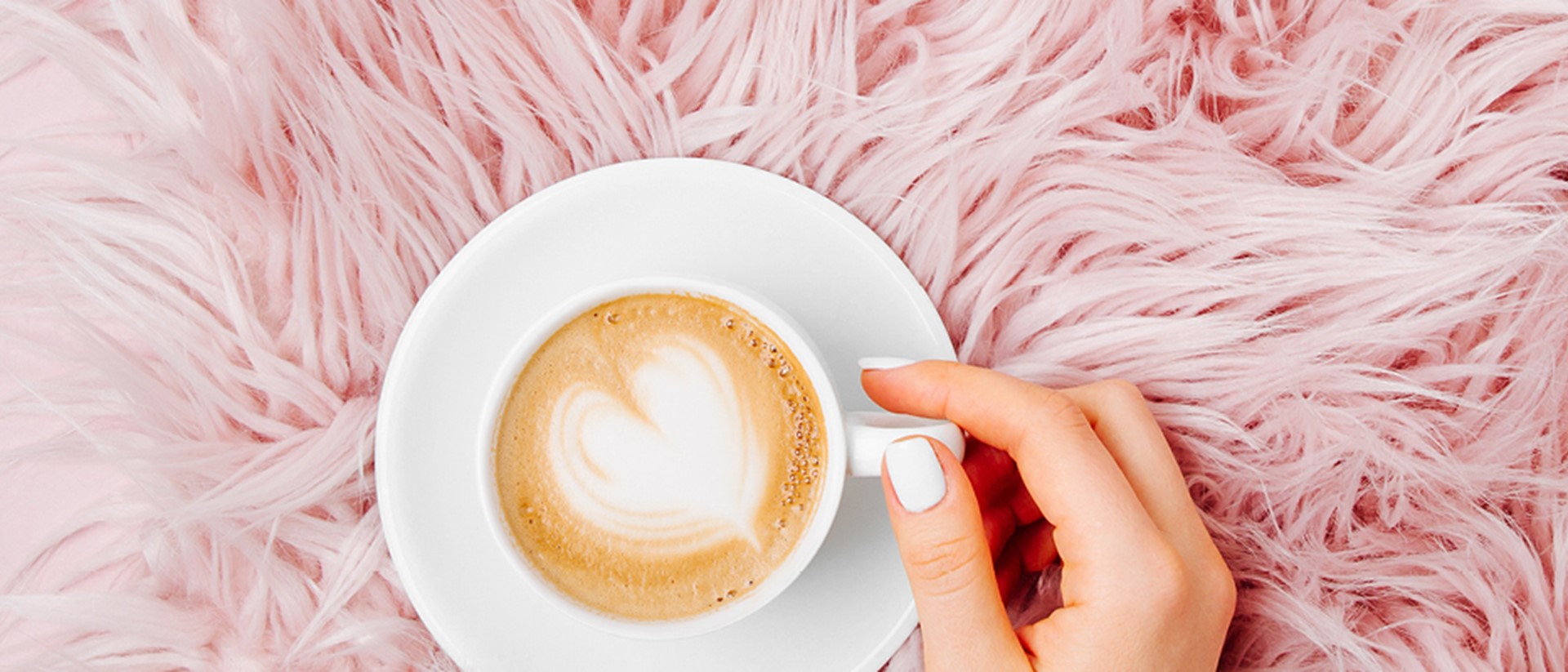 Top down image of fresh mug of coffee on a fluffy pink background