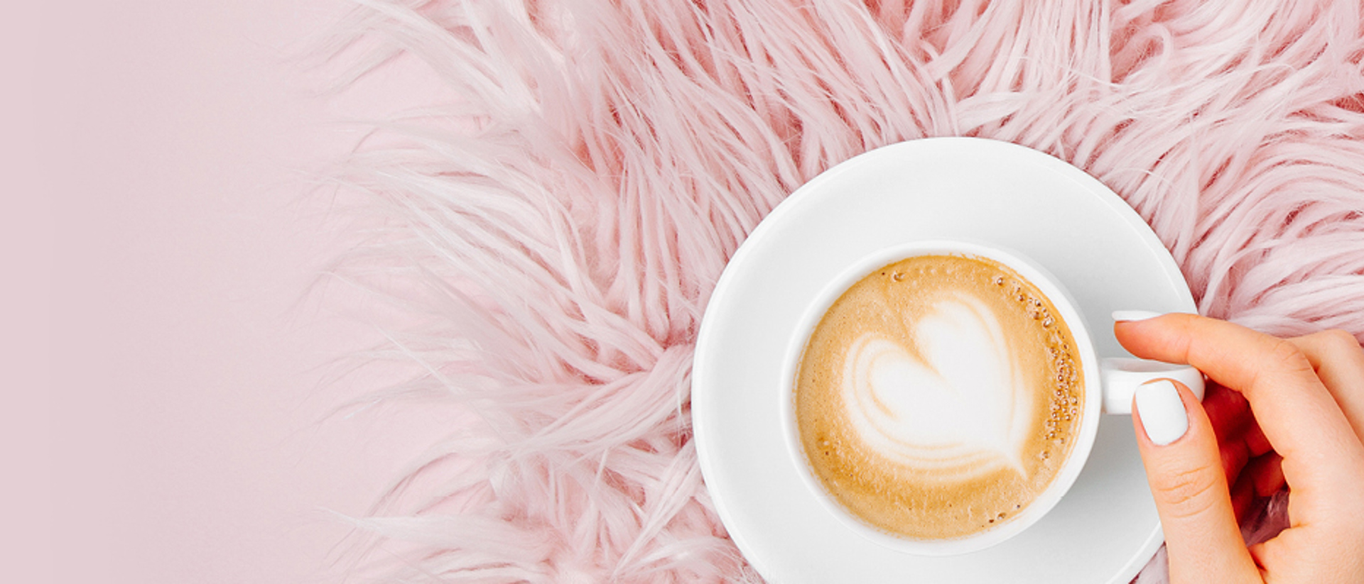 Top down image of fresh mug of coffee on a fluffy pink background