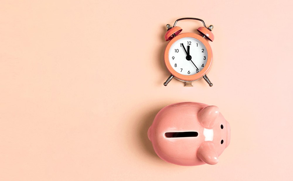 Image of an alarm clock and a piggy bank against an orange background