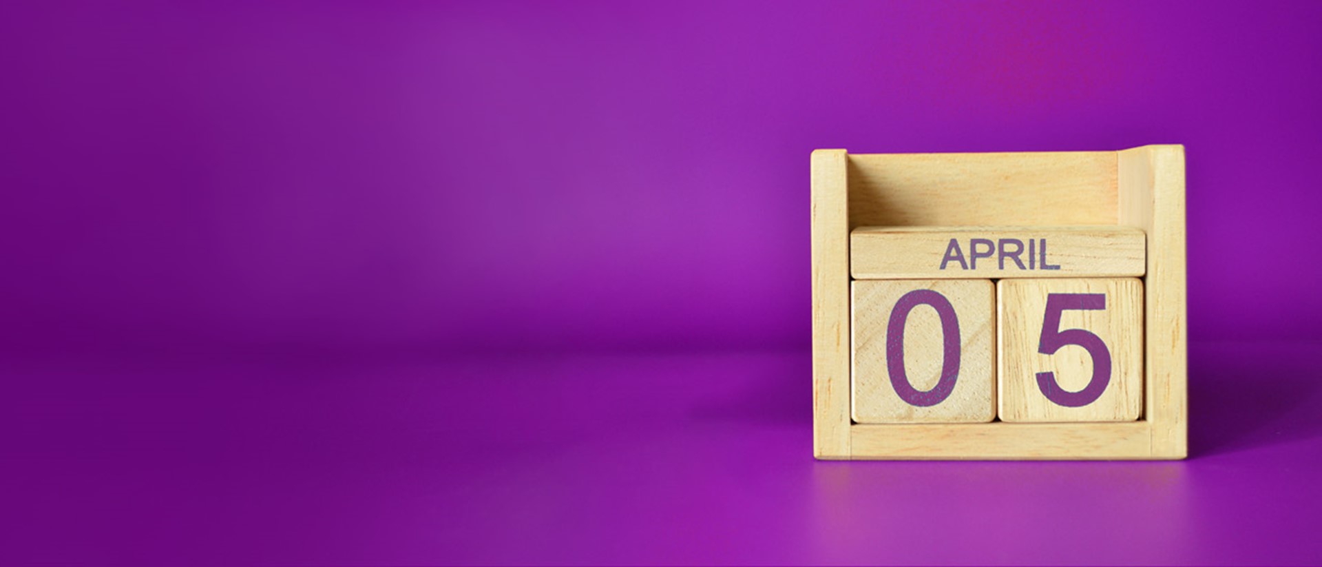 Wooden calendar block with the date of 5th April against a purple background