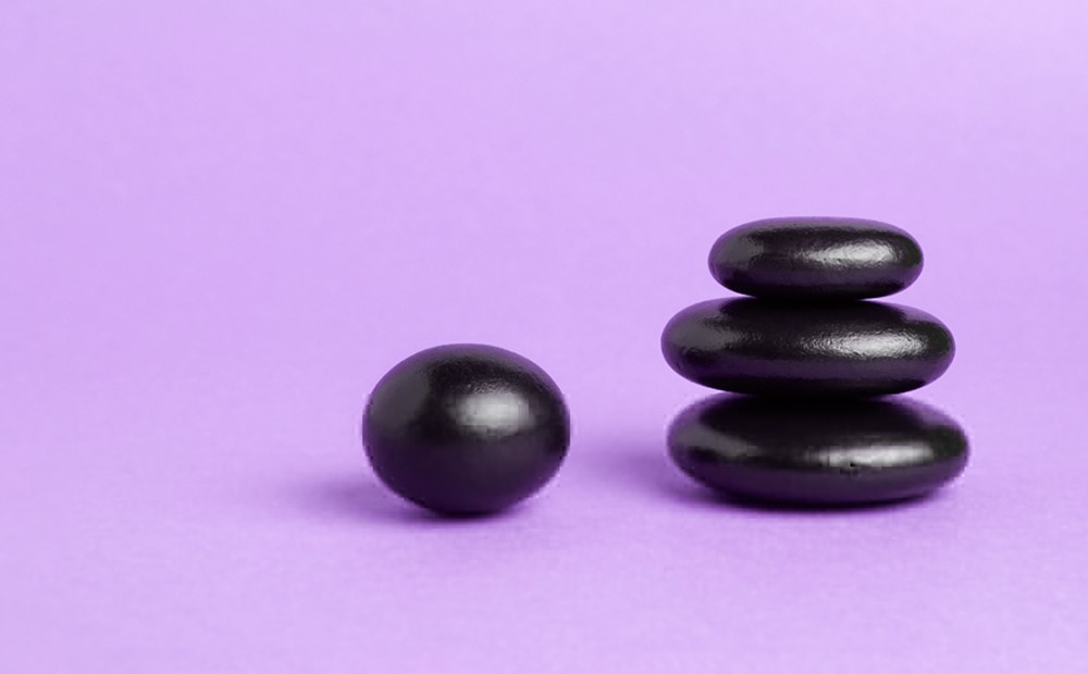 Image of a stack of black pebbles against a purple background
