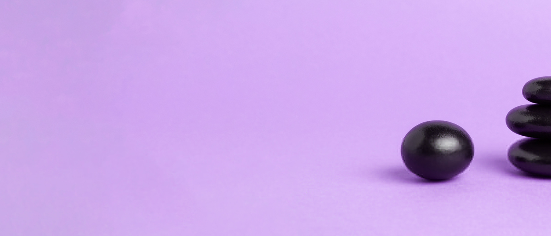 Image of a stack of black pebbles against a purple background