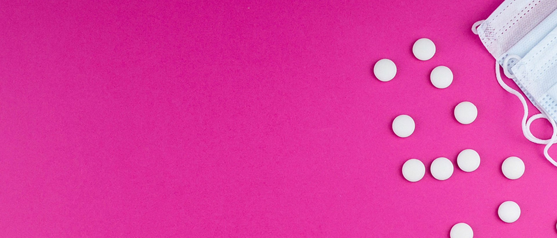 Image of a white surgical mask and pills on a pink background