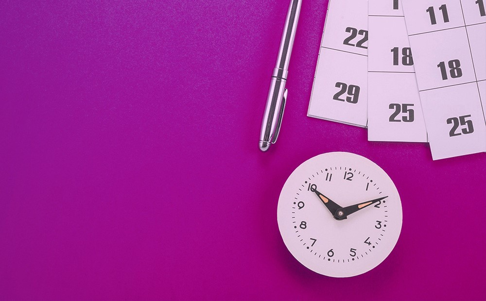 Image of a pen, calendar and clock on a purple background