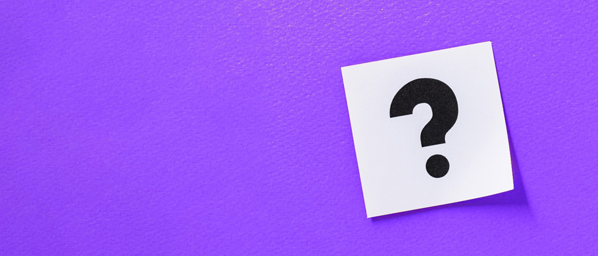 A question mark on a white sticky note against a purple background