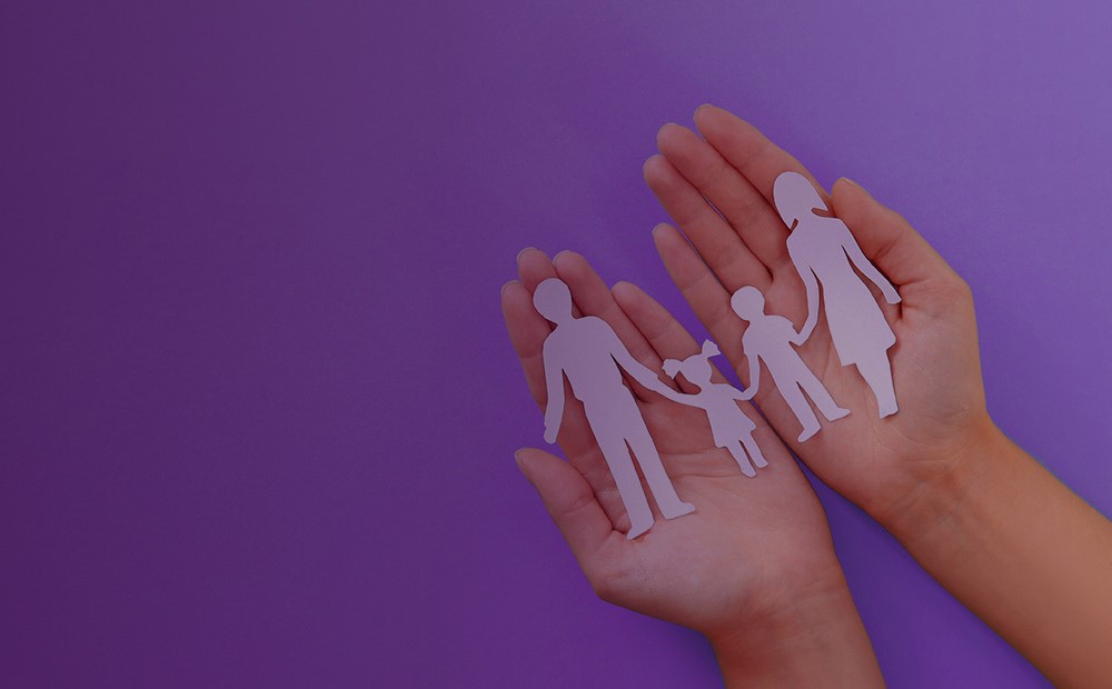 Image of a paper cut out family in the palms of a hand