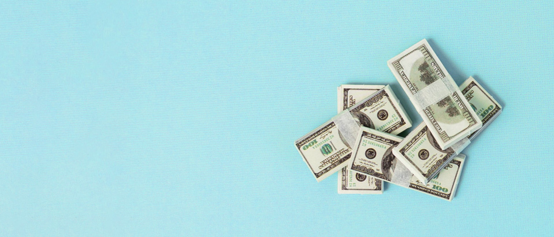 A stack of American dollar bills against a light blue background