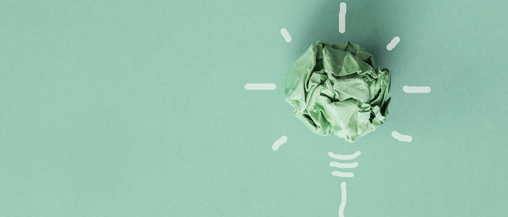 Image of a green ball of paper in a shape of lightbulb on a teal background