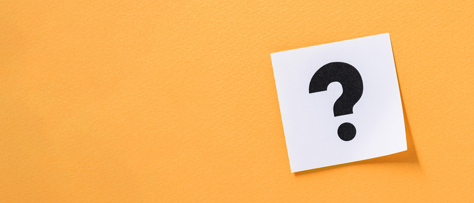 A question mark on a white sticky note against an orange background
