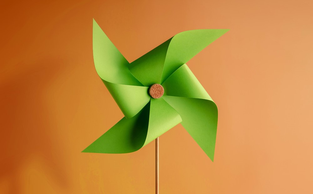 Image of a green paper fan against an orange background