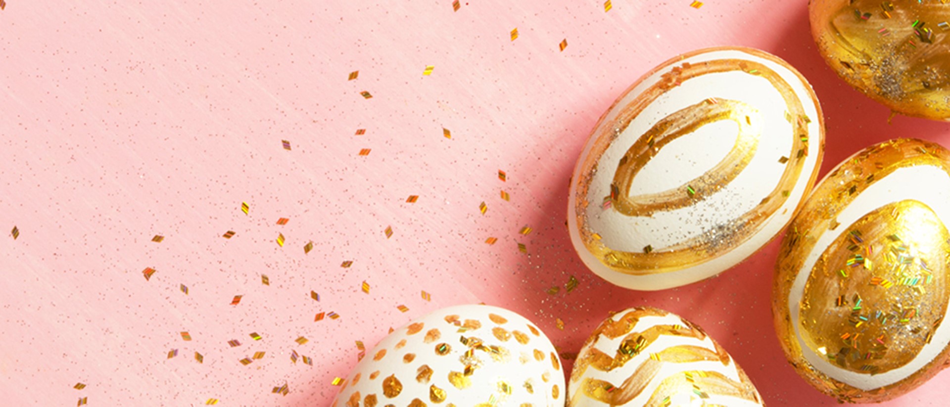 Image of eggs painted gold in different patterns on a pink background
