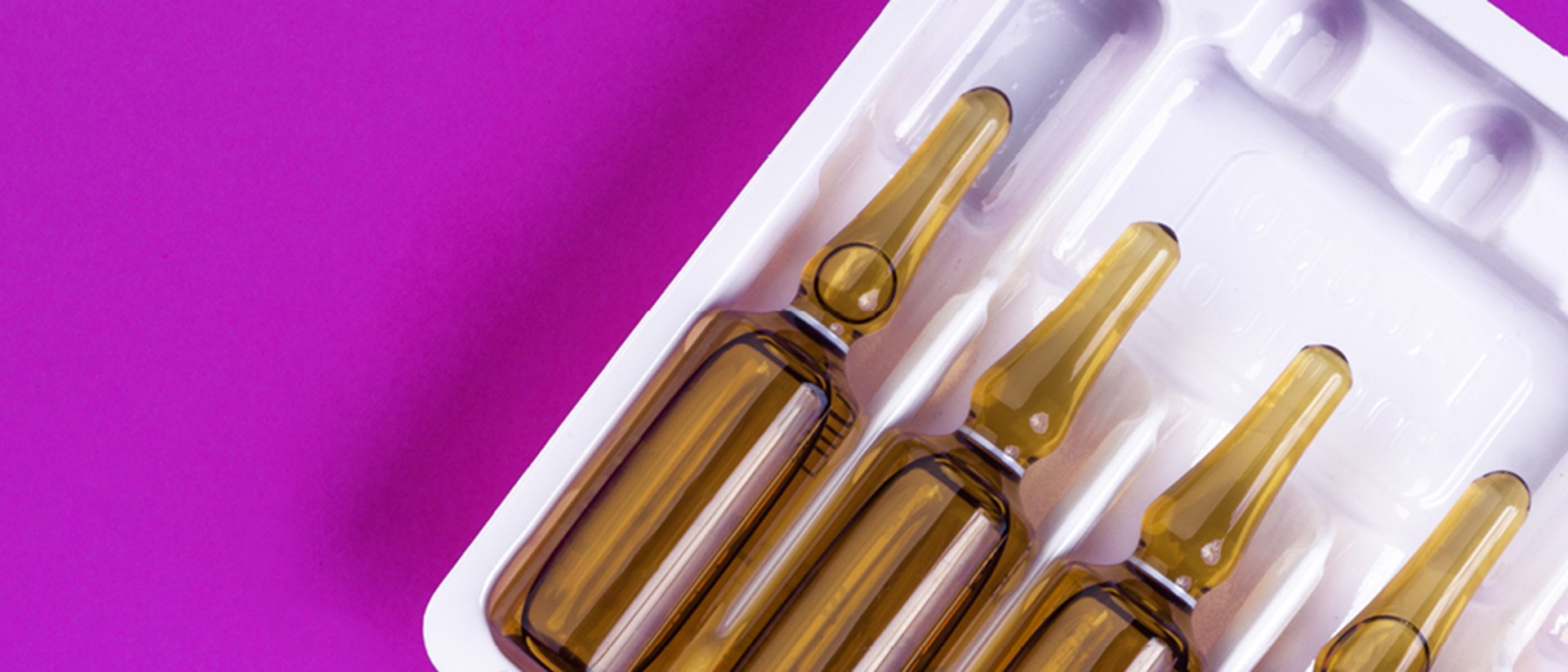 Image of glass vials on a pink background