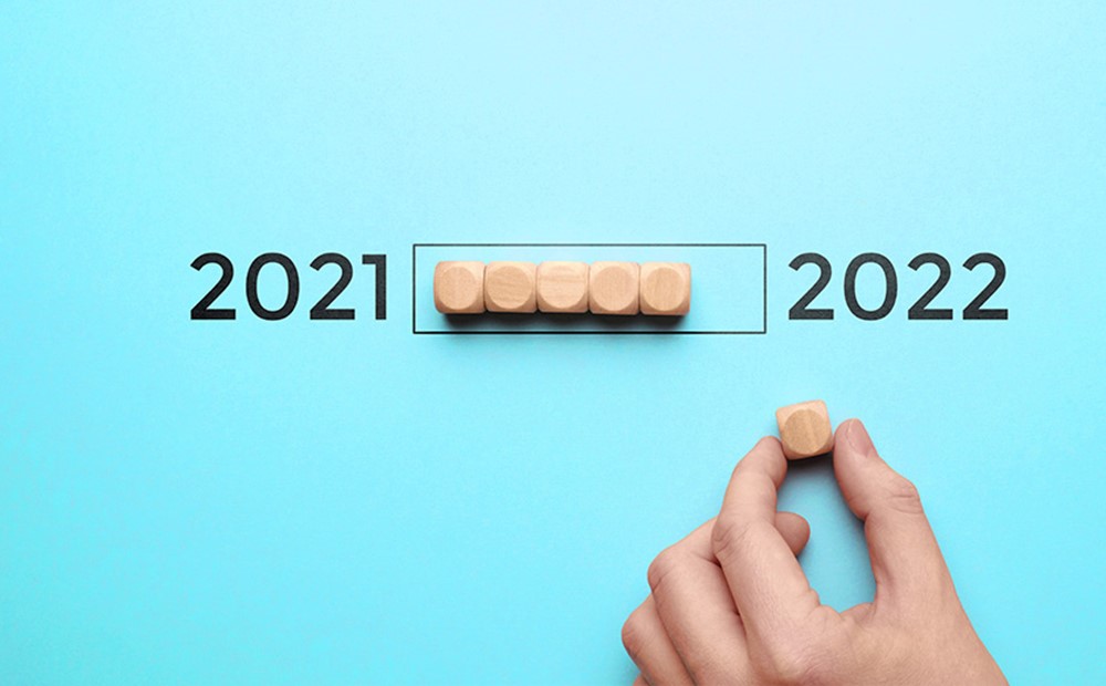 Image wooden blocks being moved from 2021 to 2022 on a blue background