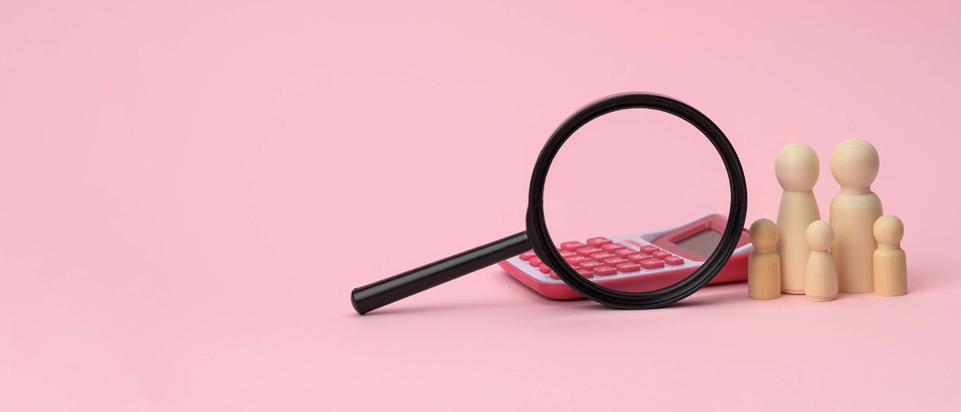 A magnifying glass, a pink calculator and a group of wooden figures against a pink background