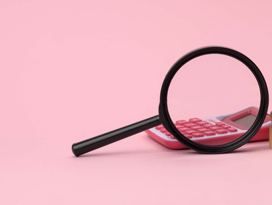 A magnifying glass, a pink calculator and a group of wooden figures against a pink background