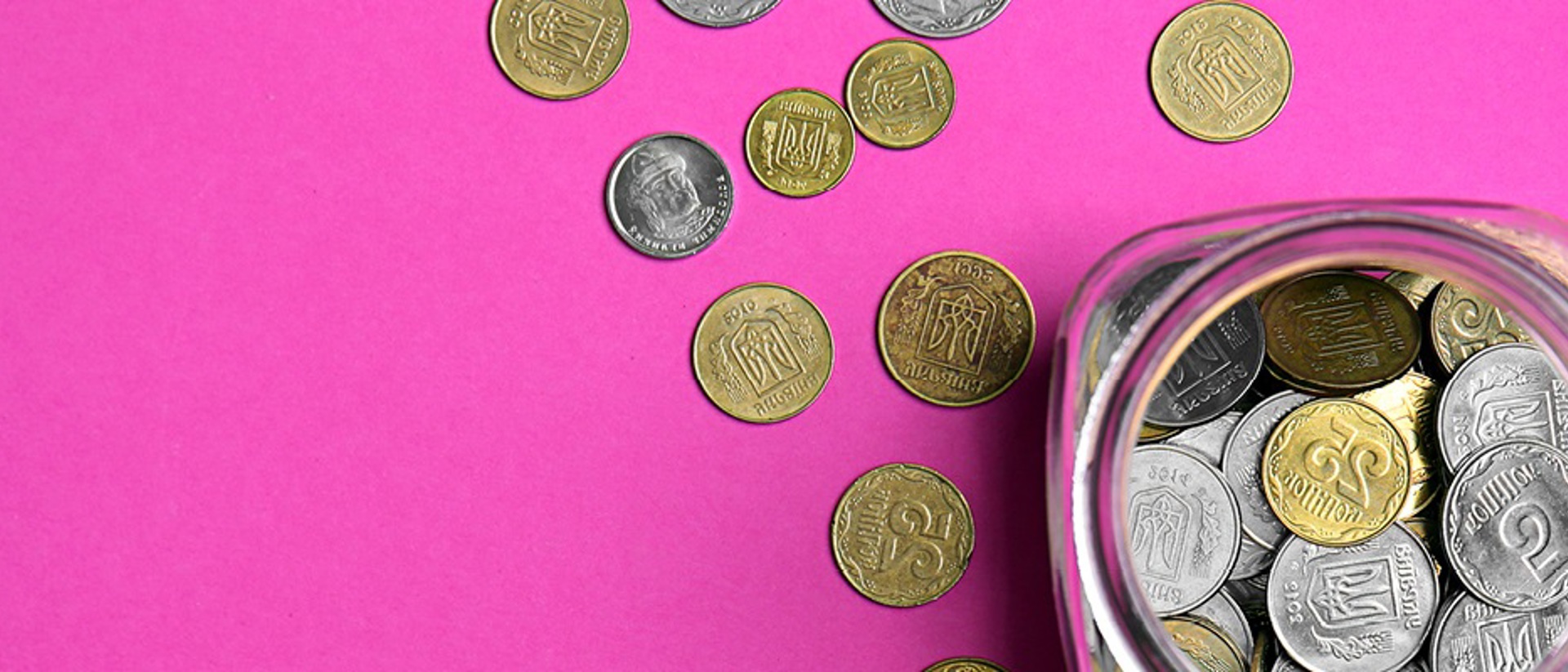 Image of coins in and out of glass jar on a pink background