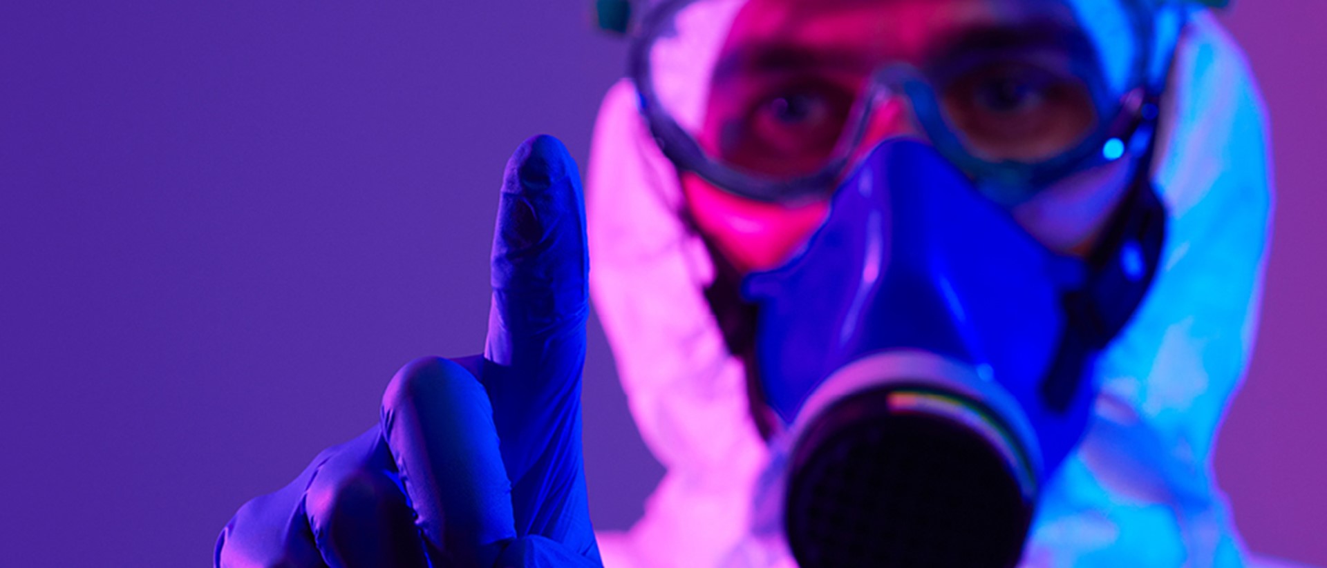 Image of man with a purple glove, wearing a gas mask on a purple background